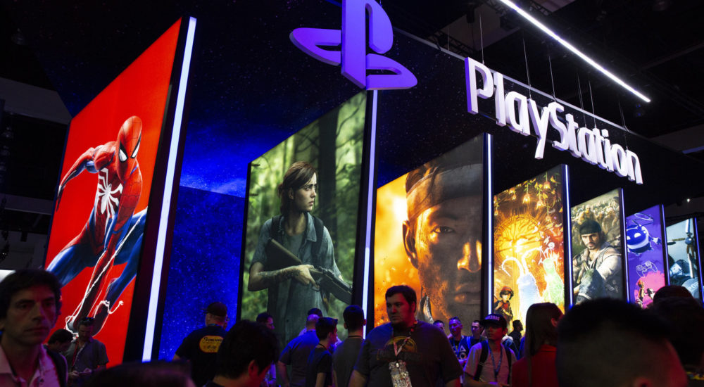 Attendees pass signage for Sony Corp. PlayStation video games during the E3 Electronic Entertainment Expo in Los Angeles, California, U.S., on Tuesday, June 12, 2018. For three days, leading-edge companies, groundbreaking new technologies and never-before-seen products is showcased at E3. Photographer: Troy Harvey/Bloomberg via Getty Images