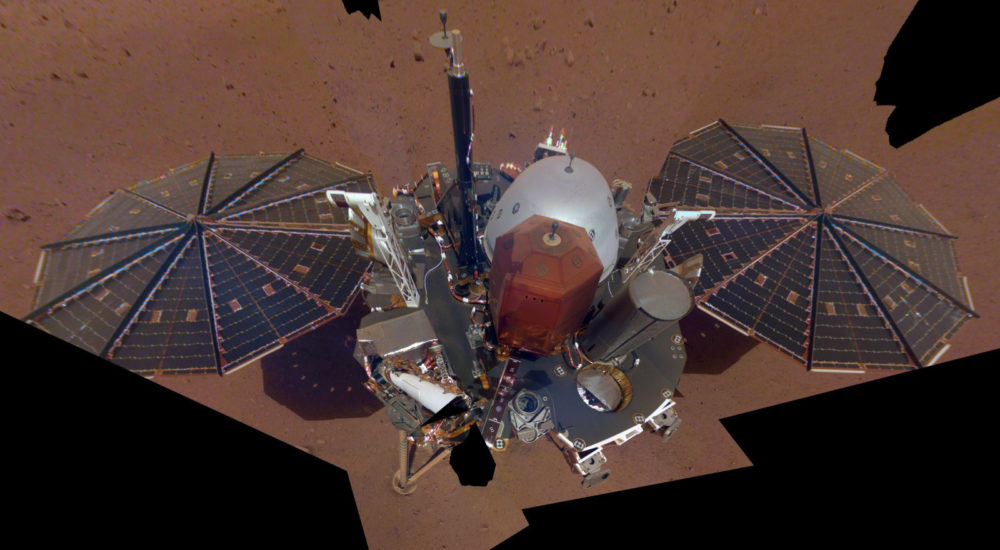 This Dec. 6, 2018 image made available by NASA shows the InSight lander. The scene was assembled from 11 photos taken using its robotic arm. The two white stalks between the center and the solar panels are weather sensors. Starting Tuesday, Feb. 19, 2019, NASA’s Jet Propulsion Laboratory is posting the high and low temperatures online, along with wind speed and atmospheric pressure from the InSight lander. (NASA via AP)