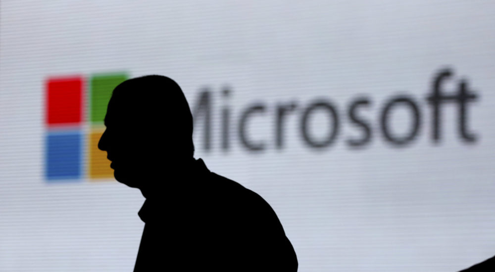 An unidentified man is silhouetted as he walks in front of Microsoft logo at an event in New Delhi, India, Tuesday, Nov. 7, 2017. (AP Photo/Altaf Qadri)
