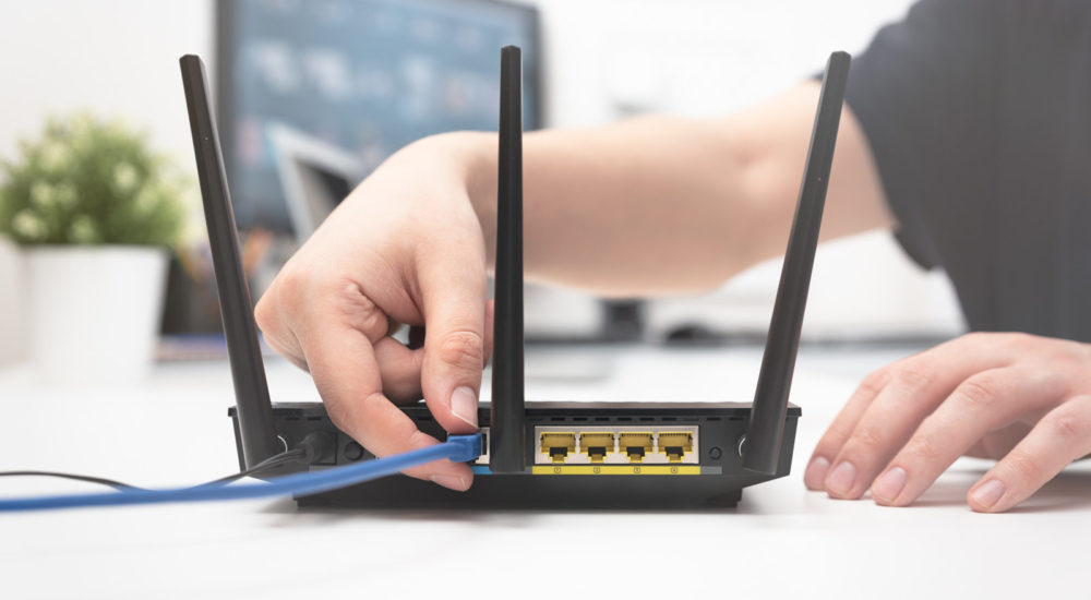 Man connects the internet cable to the router's socket. Fast and wireless internet concept