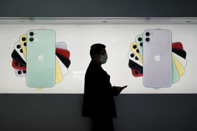 A man wearing a mask walks past an Apple Store in Hong Kong, Wednesday, Feb. 19, 2020. Russia says it will temporarily ban Chinese nationals from entering the country amid the outbreak of the new virus centered in China that has infected more than 73,000 people. (AP Photo/Kin Cheung)